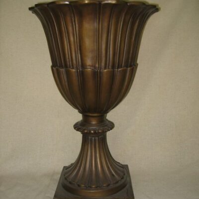 A large cast bronze Greek Roman style urn on a stand.