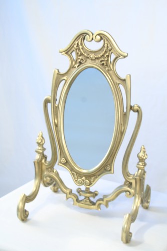 An Antique Silver Rocco mirror on a white surface.