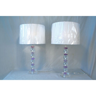 A pair of lamps with white shades and pink beads.