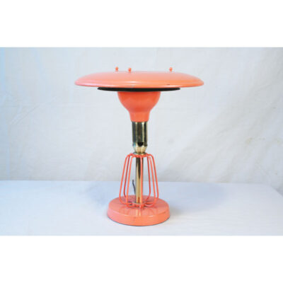 A pink table lamp sitting on top of a white surface.
