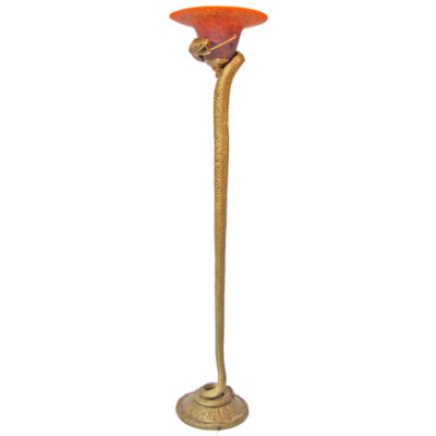A gold colored metal lamp with an orange glass shade.