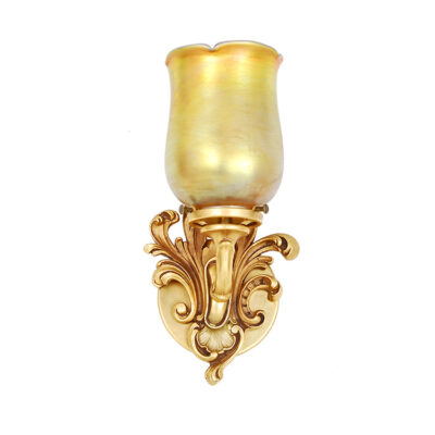 A gold colored wall sconce with a glass shade.