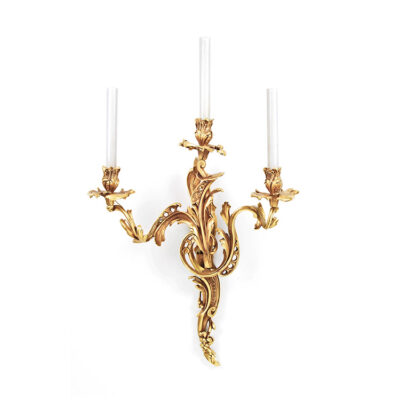 A gold wall mounted candle holder with three candles.